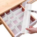 "Adjustable white drawer divider organizer holding folded clothes in wooden dresser drawer"